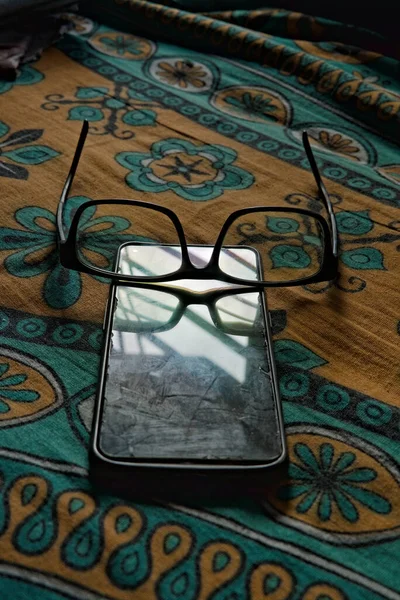 a black colored rim spectacle kept over a smartphone