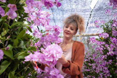 Bir yaz günü bahçede pembe çiçekli olgun bir kadının portresi.