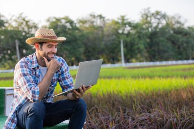 Çiftçi tarlada bilgisayarla çalışıyor.