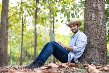 Ormanda Dizüstü bilgisayar kullanan, Çevresel Veri Toplama ve Sürdürülebilir Orman Uygulamaları İçin Dijital Teknolojiyi Kucaklayan Çiftçi