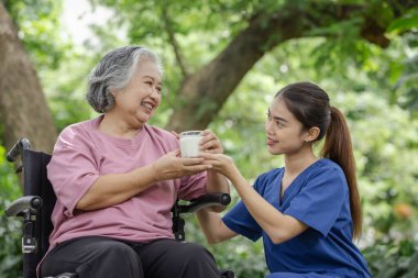 Bakıcı ile Soya Sütünün Tadını Çıkaran Yaşlı Kadın: Açık havada Sağlıklı Beslenme ve Arkadaşlığı Destekleme
