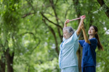 Hemşire Uzatma Egzersizinde Yaşlı Kadın Dayanıklılık Bandını Açık havada Kullanarak, Hareket ve Sağlık Sağlığını Destekliyor