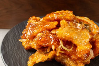 Tatlı ve çıtır çıtır Guo Bao Rou ve siyah tabakta sebzeler.