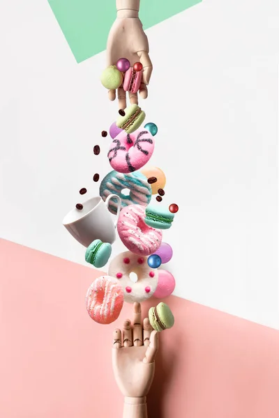 木製モデルの手の間にお菓子やコーヒーを盛り合わせ 複合画像 バランス 浮遊感 シュールなカット ペーストのコラージュ ミクストメディア 層状のパステルの背景の垂直組成 — ストック写真