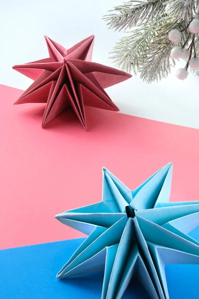 Vibrant origami paper stars, handmade DIY Christmas decorations. Self made Xmas stars made from vibrant colored paper on layered background. Handmade decorations for holiday season. Low impact hobby.