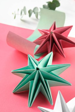 Canlı origami kağıtları, el yapımı Noel süslemeleri. Self, katmanlı arka planda canlı renkli kağıttan yapılmış Xmas yıldızları. Tatil sezonu için el yapımı dekorasyonlar. Düşük etki hobisi.