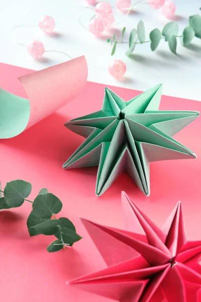 Vibrant origami paper stars, handmade DIY Christmas decorations. Self made Xmas stars made from vibrant colored paper on layered background. Handmade decorations for holiday season. Low impact hobby.