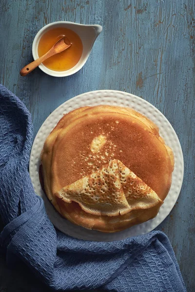 Russian pancakes with honey. Flat lay, top view on aged cracked grey mint blue wood with towel. Traditional breakfast foor, sweet snack. Recipe. Overhead food shots.