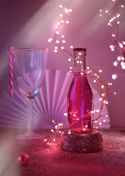 一小瓶玫瑰 粉红色的葡萄藤或覆盆子伏特加在石座上 圣诞节庆祝的概念 采购产品酒杯和圣诞节的冬天装饰 节日的轻花环 黑色背景的纸扇 — 图库照片