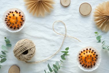Mandalinadan el yapımı karanfilli kokulu pomander topları. Kahverengi kabartma kağıdından el yapımı kağıt yıldızlar. Beyaz, okaliptüslü tekstil ürünlerinden uzak dur. Tahta daireler, kenevir kordonu.