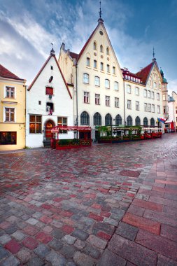 Tallinn, Estonya 'da ortaçağ mimarisi. Tarihi evlerdeki sokak kafeleri, restoranlar, kahve dükkanları. Güneşli yaz gününde Tallinn eski kasabasında yağmurdan sonra mavi gökyüzü. Ön planda ıslak patika.