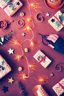 Koyu kırmızı Noel arkaplanı. Burgundy, carmine, garnet monokromatik düz badem ezmesi tatlılar, paketlenmiş hediye kutuları, okaliptüs, fındık, yıldızlar, mum ışığı ve elektrik çelengi..