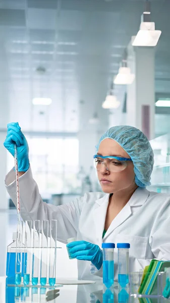 白人女性科学者は科学研究施設で精力的に活動している 彼女は白い研究室のコートと保護手袋を着ている — ストック写真