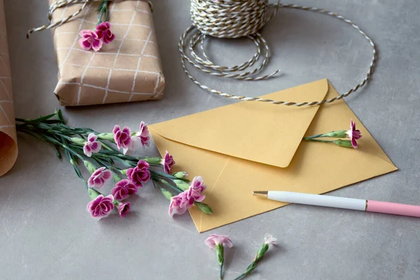 封筒と自己新鮮なカーネーションの花とグリーティングカードの概念を作った 包装されたギフト 紙のポストカード 紙封筒 コード はさみ 紫色のカーネーション — ストック写真