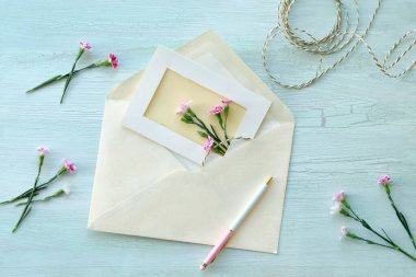 Zarf ve kendi kendine yapılmış tebrik kartı konsepti, taze karanfil çiçekleriyle. Paketlenmiş hediye, kağıt kartpostal, kağıt zarf, kablo, makas ve mor karanfiller..
