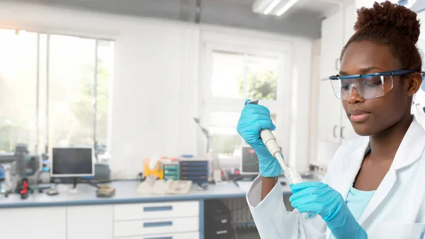 穿着实验室外套在实验室与管道一起工作的非洲女科学家或研究生 — 图库照片