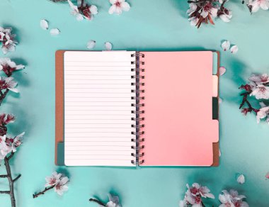 Boş not defterini ve pembe badem çiçeklerini aç, arkaplanda kopya alanı olan bahar örtüsü, metin, çizim veya nane yeşili kağıt arkaplan üzerindeki harfler için yer ile kitap modellemesi yap.