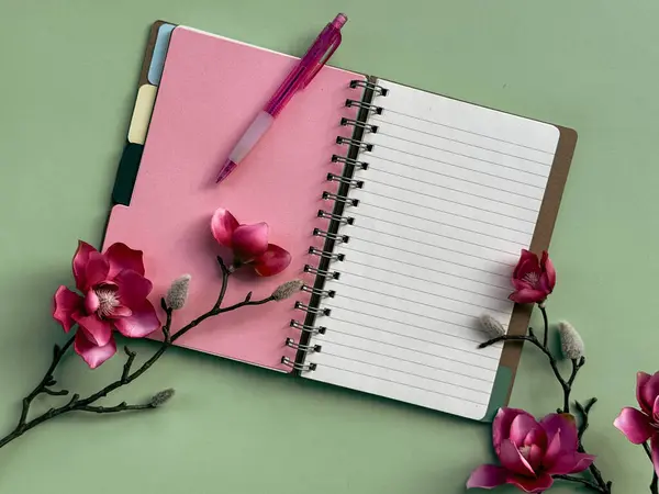 一个粉红色的笔记本 书页装帧整齐 放在框架的中心 上面放着一支钢笔 粉红木兰花 — 图库照片