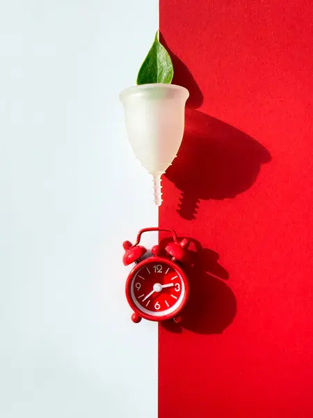 Een Herbruikbare Siliconen Menstruatiecup Wekker Een Rood Wit Papier Bovenaanzicht — Stockfoto