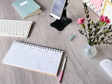 Planlayıcı, Klavye, Akıllı Telefon ve Ahşap Masadaki Çiçeklerle Düzenli Çalışma Alanı.