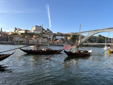 Traditional Rabelo Boats on Douro River with Porto Cityscape and Luis I Bridge. clipart