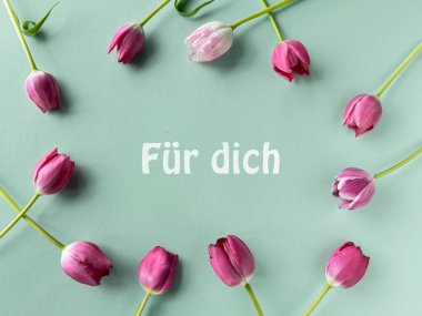 Almanca Herzlichen Glckwunsch anlamına gelen ahşap çerçeveli pembe laleler ve pastel mavi arka planda siyah kalp şekilleriyle çevrili, tebrikler..