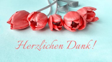 Açık mavi bir yüzeye yerleştirilmiş kırmızı laleler ve Alman metni 