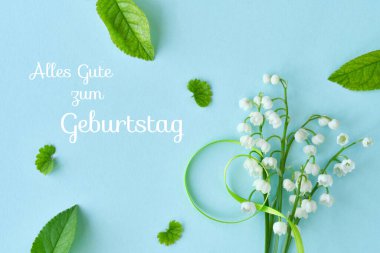 Vadi çiçekleri, açık mavi arka planda dağınık yeşil yapraklarla çevrili yeşil bir kurdeleyle bağlanmış. Almanca 