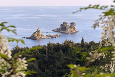Adriyatik Denizi 'ndeki Saint Nedelja adalarının Karadağ' ın kıyı şeridinden görülen manzarası. Canlı yeşillikler ve çiçek açan çiçekler tarafından çerçevelenmiş.