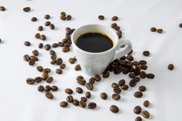 A white cup of coffee on a white background with coffee beans