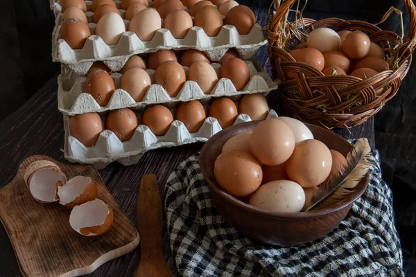 Chicken eggs in a clay plate and trays on the table.