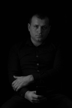Black and white photo of a man in a shirt on a black background.