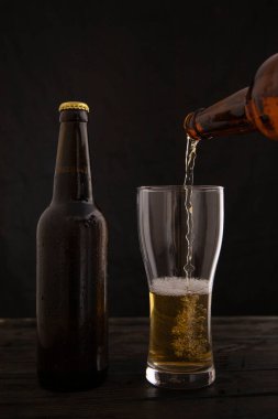 Bira bir siyah arka plan üzerine bir bardak içine dökme