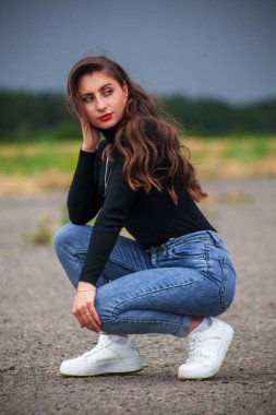 Fırtına bulutlarının arkasında kot pantolonlu güzel bir genç kız..