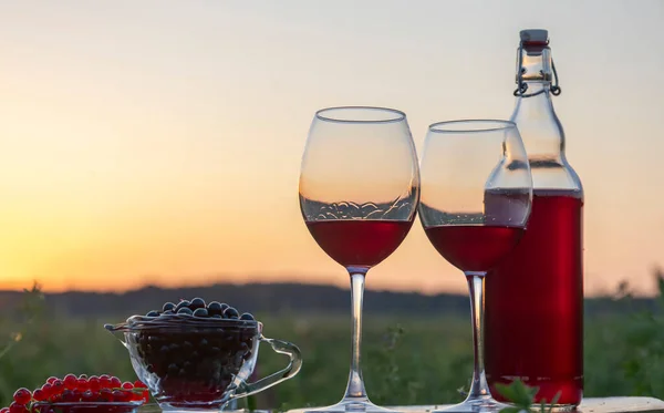 Wine in a glass and bottle on the background of the sunset.