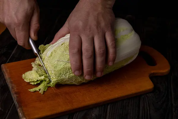 Cutting vegetables. Male hands cutting cabbage on a cutting board