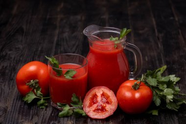 Domatesli bardakta taze domates suyu, koyu arkaplanda maydanoz.