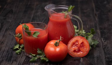 Domatesli bardakta taze domates suyu, koyu arkaplanda maydanoz.