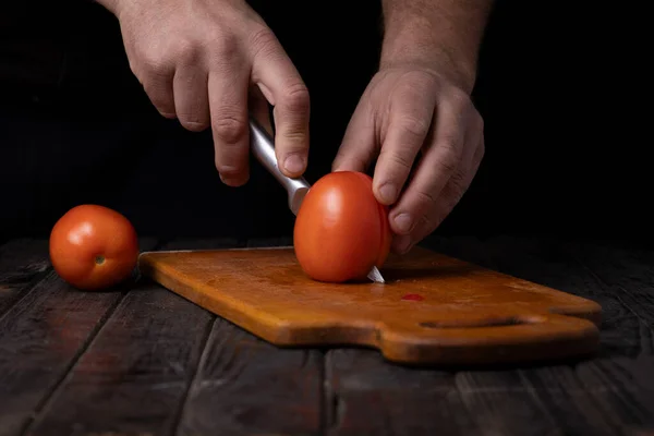 Cutting vegetables. Male hands cutting tomatoes on a cutting board