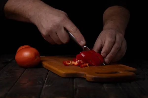 Cutting vegetables. Male hands cutting tomatoes on a cutting board