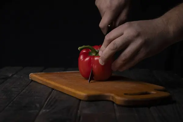 Cutting vegetables. Male hands cutting sweet red pepper on cutting board