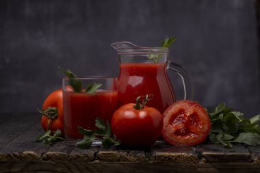 Domatesli bardakta taze domates suyu, koyu arkaplanda maydanoz.