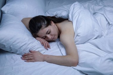Kız beyaz bir yatakta uyuyor..