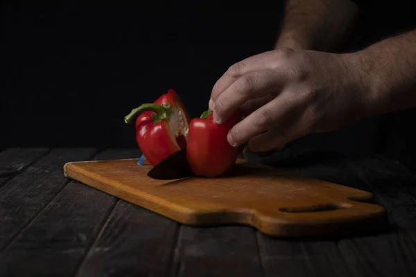 Cutting vegetables. Male hands cutting sweet red pepper on cutting board