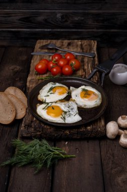 Domuz pastırması ve sebzeli sahanda yumurta, dökme demir tavada eski, ahşap masa arka planında.,