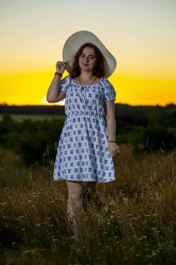Tarlanın arka planında şapkası olan bir kız.