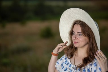 Tarlanın arka planında şapkası olan bir kız.