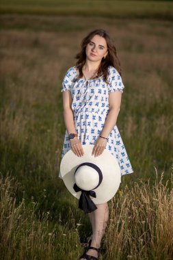 Tarlanın arka planında şapkası olan bir kız.