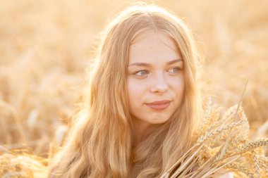 Güneşin altında buğday tarlasında güzel bir Ukraynalı kız.