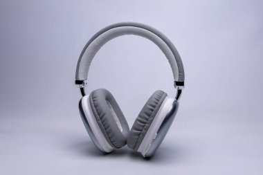 Şık gümüş ve beyaz kablosuz kulaklıklar müzik dinlemeye ya da çağrılara cevap vermeye hazır.